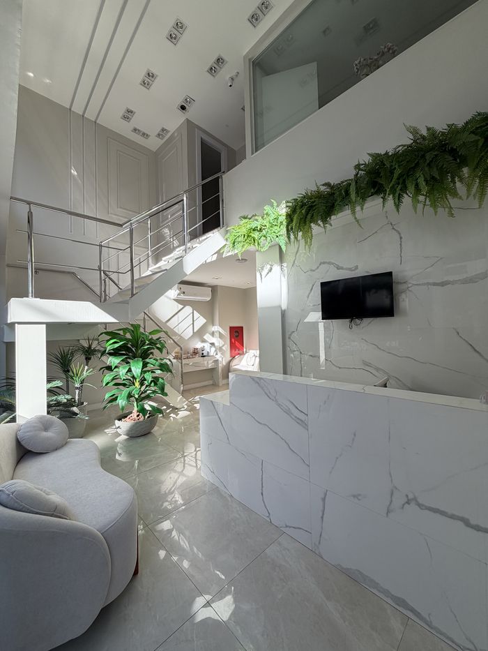 Hall de entrada da Clínica Zeni, com balcão de mármore, escada e jardim vertical